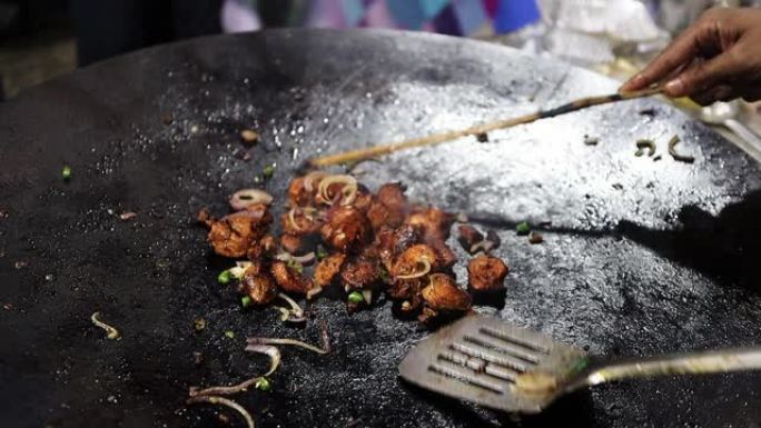 小块鸡肉在洋葱大煎锅上油炸，用于准备kathi烤肉串卷