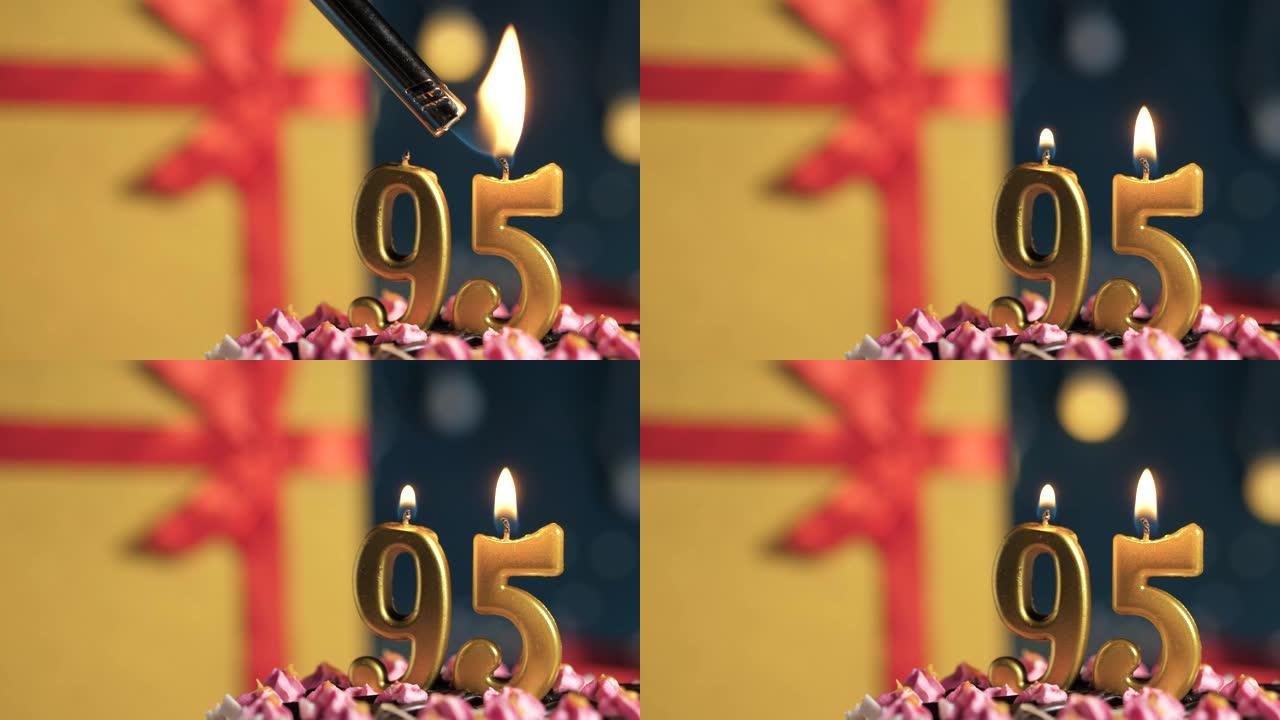 生日蛋糕95号点火器燃烧的金色蜡烛，蓝色背景礼物黄色盒子用红丝带绑起来。特写和慢动作