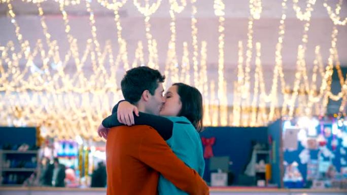 圣诞节时，年轻的幸福夫妇在溜冰场上接吻
