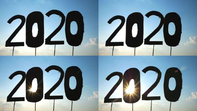 回收纸板的剪影变成2020的数字，在蓝天背景和阳光照耀着文本。新年和庆祝活动的概念。