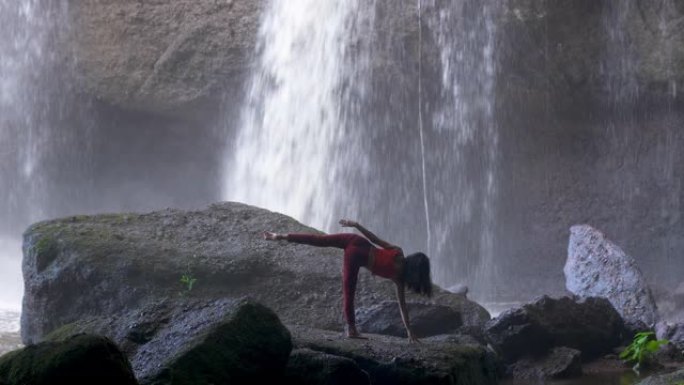 亚洲女子在瀑布练习或做瑜伽。美丽的风景，自然的背景，泰国。女性专业瑜伽
