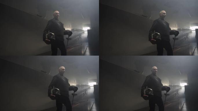 一名身穿黑色击剑制服的老人在黑暗多雾的训练馆里摆姿势