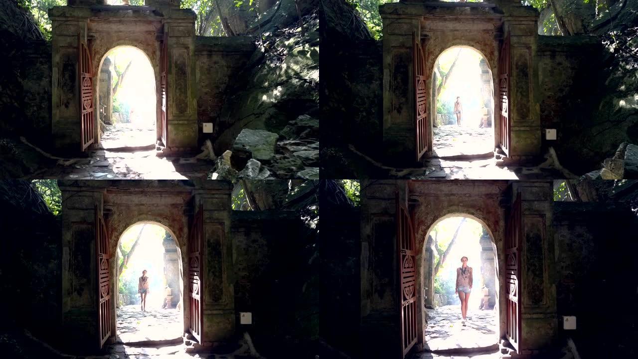 女孩游客在阳光下接近洞穴石拱门