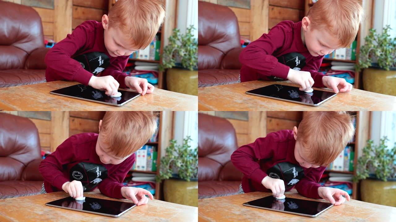 用抗菌一次性湿巾或纸巾清洁数码平板电脑的小男孩