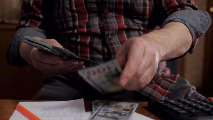 退休男子考虑金钱。一位老人数着美元钞票的特写镜头。