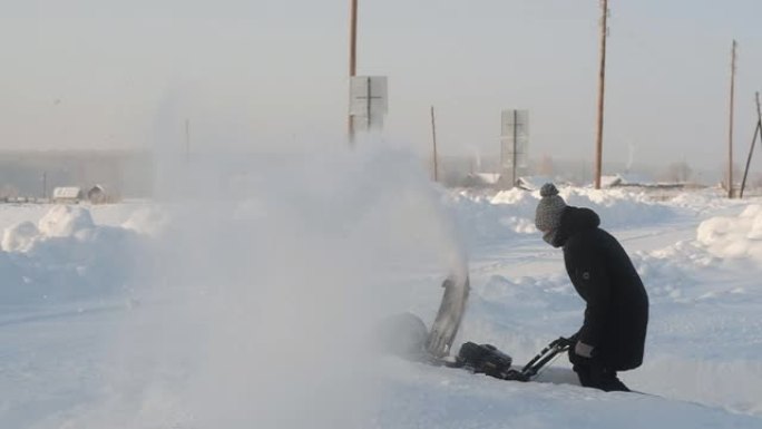 穿着冬装的年轻人用除雪设备清除街道积雪。