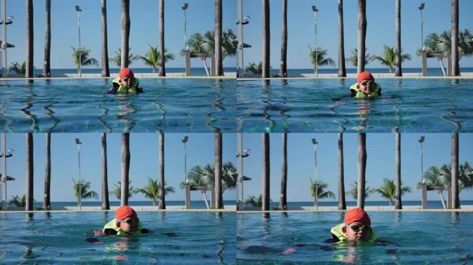 快乐的亚洲儿童男孩在室内游泳池度假村穿救生衣和游泳衣穿游泳镜。节日快乐。慢动作