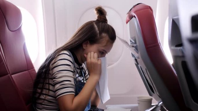 飞机上的少女在纸袋里呕吐。乘坐飞机的旅行者恶心。恶心飞机上的乘客。飞机上的湍流。