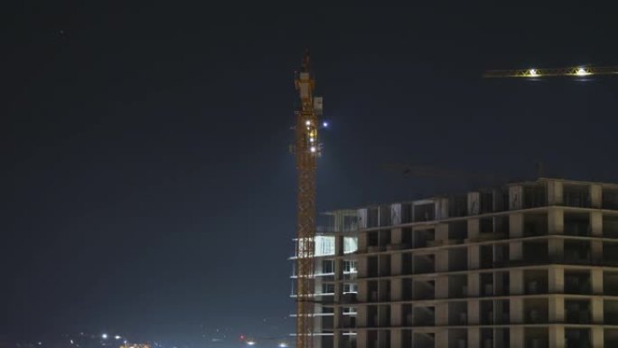 夜间建筑施工。延时。带有照明的建筑工地上的塔式起重机