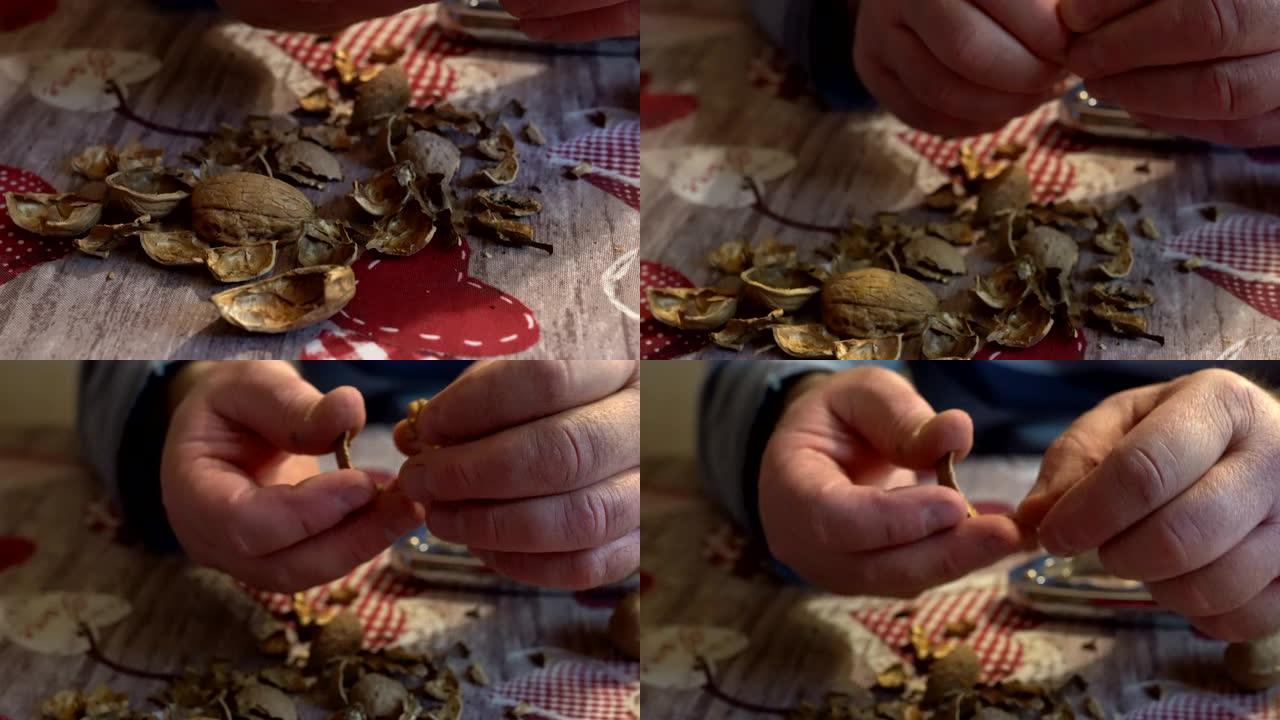 桌子上碎核桃壳的特写镜头，男人的手用坚果饼干打碎了干果。一堆去皮的坚果壳，为家庭剥健康的核桃。核桃免