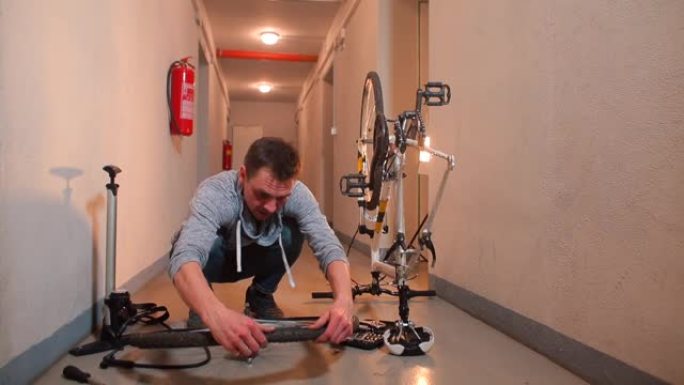 一名男子将自行车车轮放在车库的地板上。