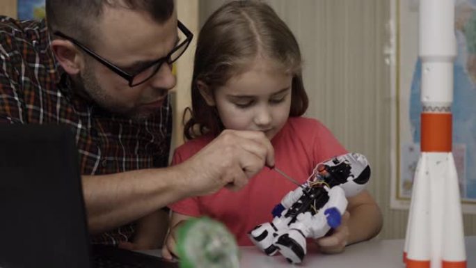女学生和老师在现代教室组装机器人。爸爸和女儿在家组装机器人。教育科学，技术儿童，编程电子机器人学校课