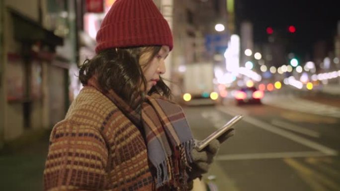 在东京市，年轻的亚洲妇女戴上羊毛帽子和围巾等出租车。