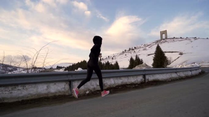 跟随穿着黑色运动服的年轻女子在山上慢跑，在顶部达到自由之弧