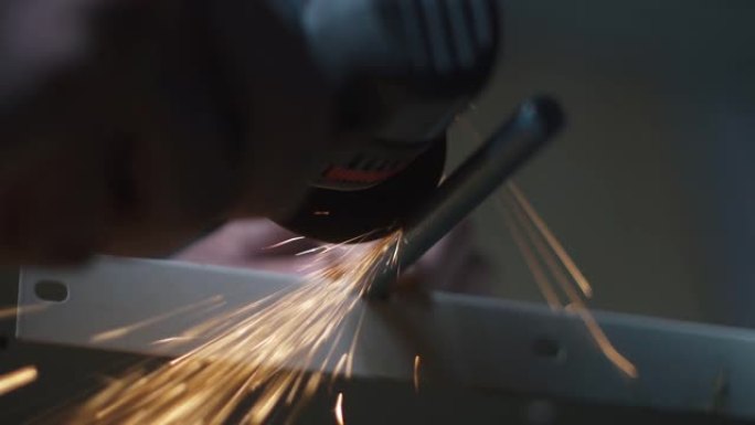 工业工人在工业工厂工作时使用角磨机切割钢材。切割金属产生的火花击中了相机。人类在植物里工作。在工业中