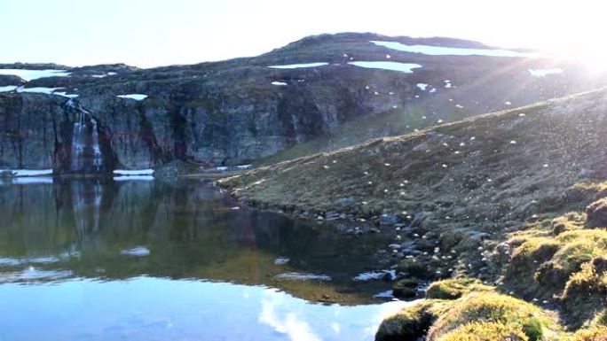 许多蚊子在雪路Aurlandsvegen附近的山湖上空飞行。慢动作视频。挪威。