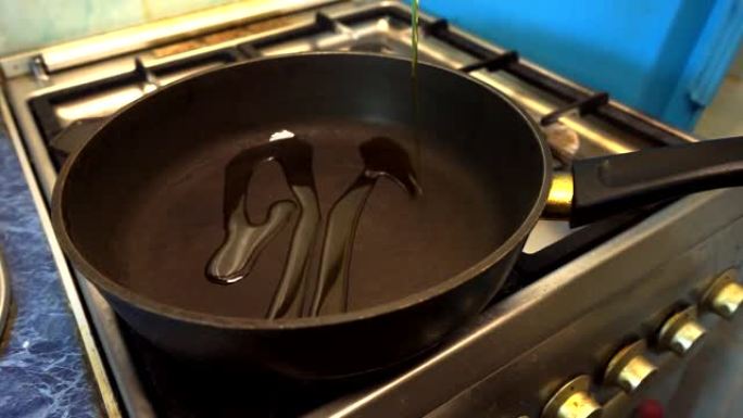 将植物油倒入煎锅中进行烹饪。带有不粘涂层的黑色平底锅立在燃气灶上。