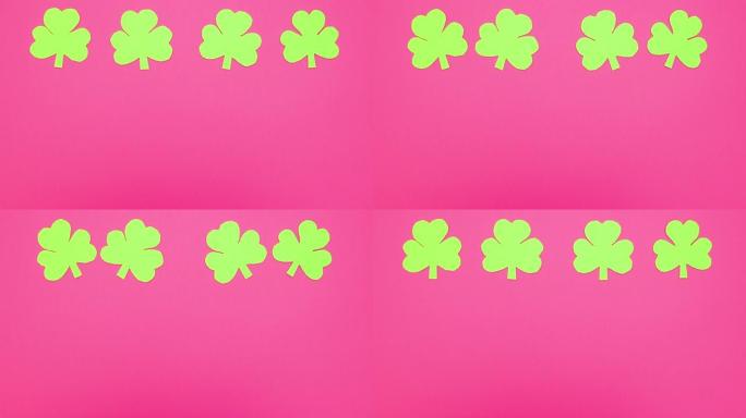 四个绿色三叶草在粉红色背景上移动-停止运动