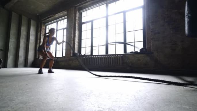 健身女孩在健身房用战斗绳锻炼