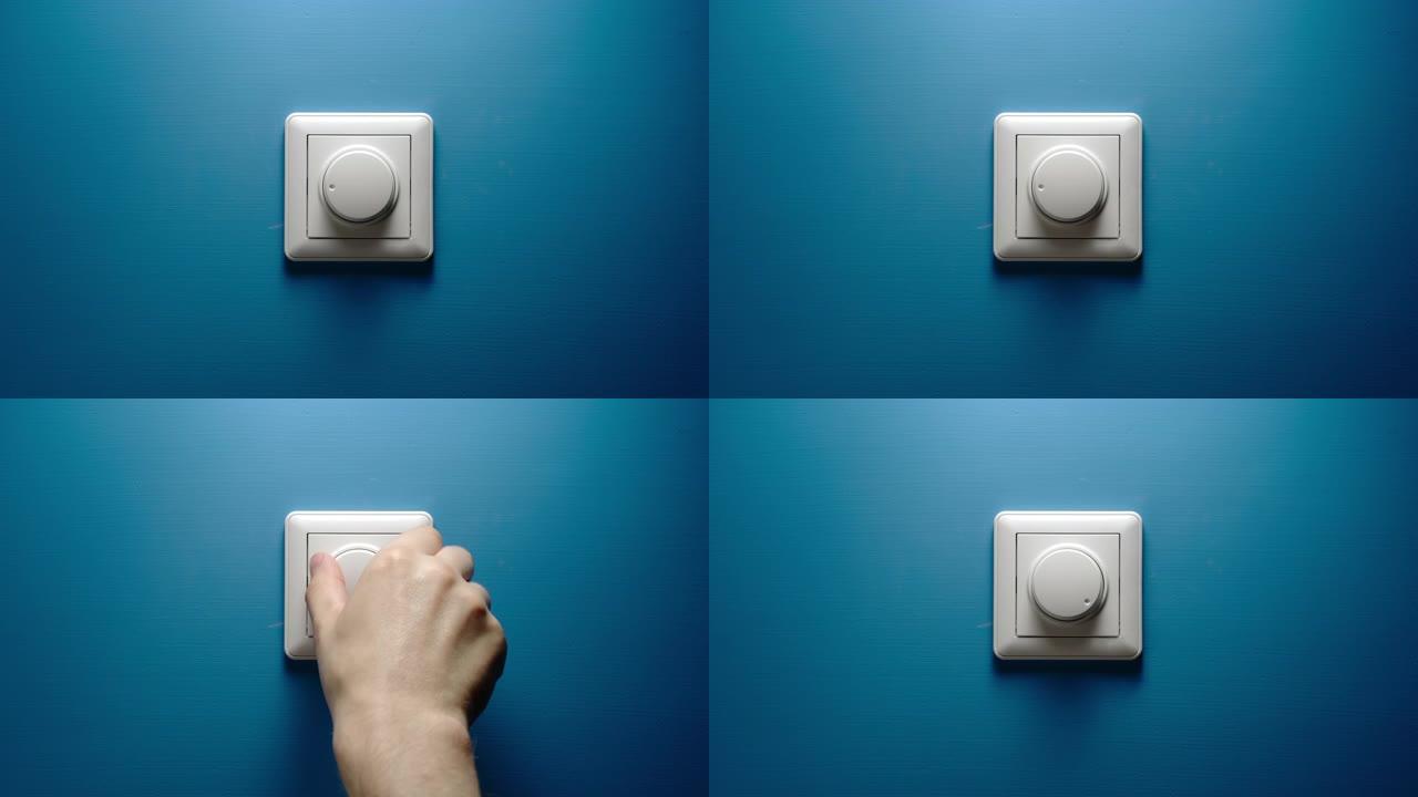 男性手转动蓝色墙壁上的调光按钮