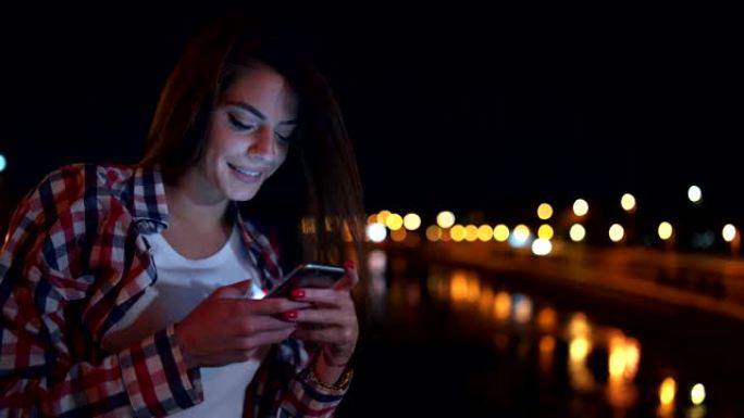 微笑的女人在河边使用手机