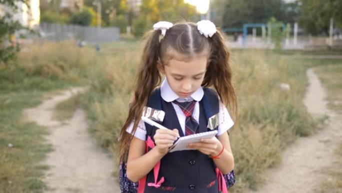 女学生放学后穿过公园回家，在笔记本上写些东西。
