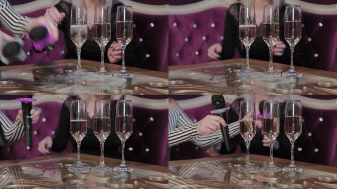 女孩用麦克风将香槟倒入桌子上的玻璃杯中