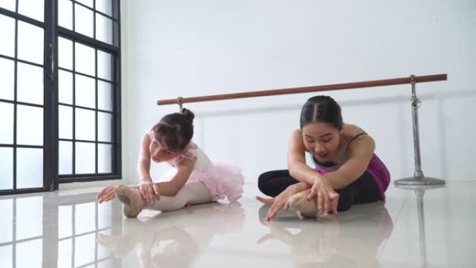 芭蕾舞女演员老师和学生坐着伸展身体和腿