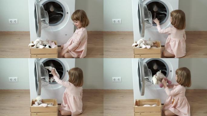 微笑可爱的3岁小女孩的肖像坐在层压地板上，打开舱门，放入洗衣机玩具进行洗涤