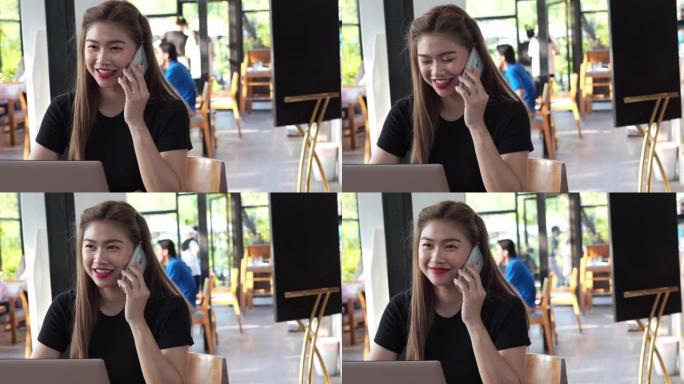 美丽迷人的亚洲女商人在咖啡店使用智能手机或手机咖啡馆通过社交媒体和在线购物微笑和幸福