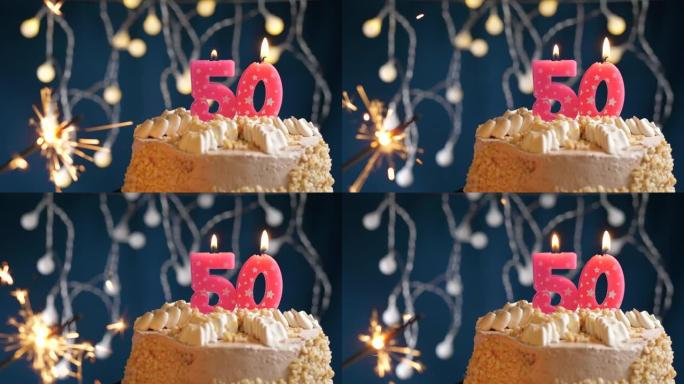 生日蛋糕，蓝色背景上有50个粉色蜡烛和烟火。慢动作和特写视图