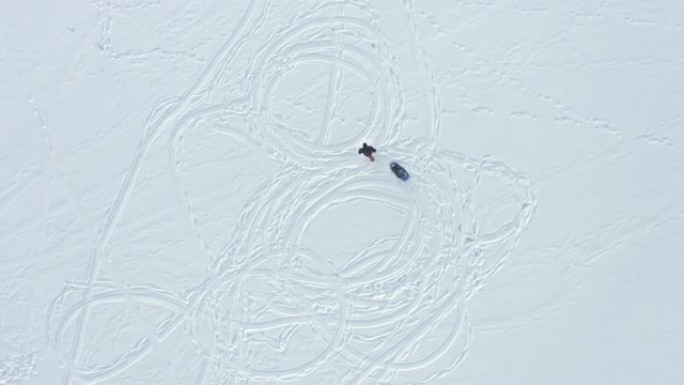 冬天父亲在湖上拉雪橇的儿子的鸟瞰图