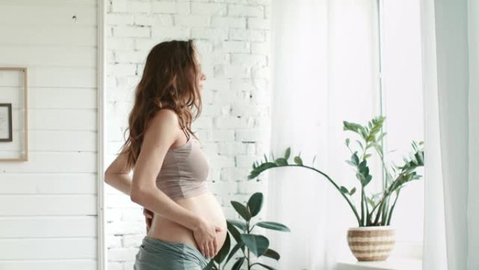 怀孕的卧室窗户。期待肚子妈妈在家抚摸肚子。