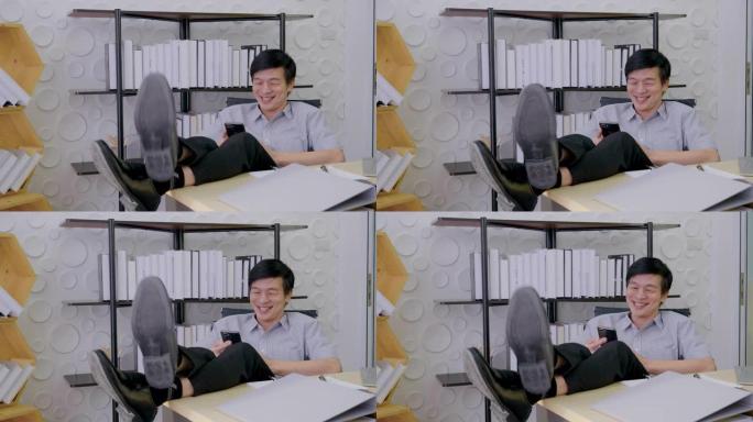 亚洲老人坐在办公室里看着屏幕手机工作，笑容满面快乐地微笑着快乐地成功