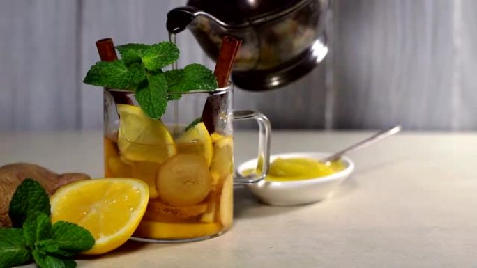 将茶壶中的热茶倒入装有柠檬，肉桂和薄荷的杯子中