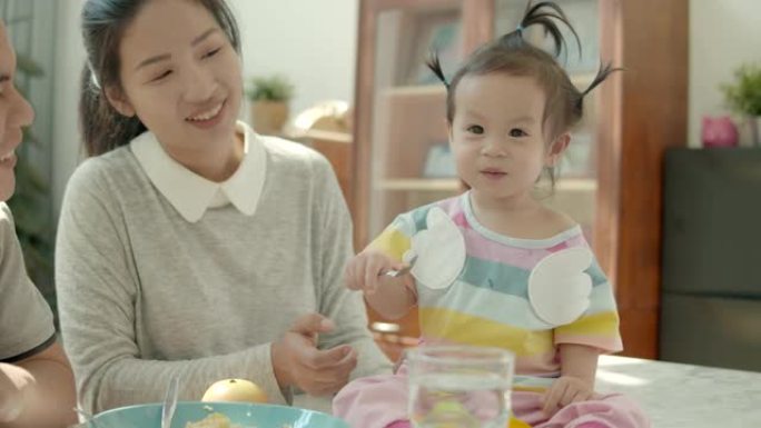 4k慢动作，亚洲成人家庭在客厅给女婴喂食物吃早餐。