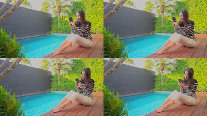 年轻的亚洲女性在室外游泳池周围使用电话