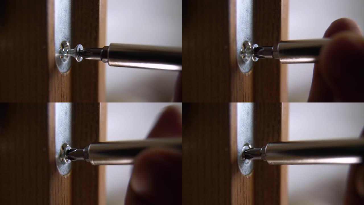 木匠修理门锁的特写。安装门把手。杂工拧紧门铰链。修理工用螺丝刀的手。锁匠将螺栓拧入木门
