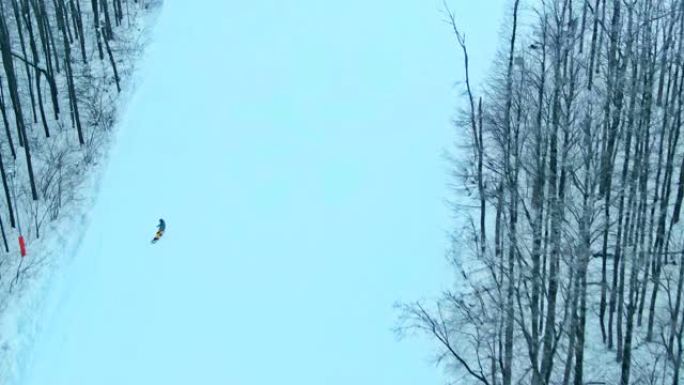滑雪板的雪道。滑雪者从白雪皑皑的下降中迅速降落在木板上。直升机的鸟瞰图。从上方观看。