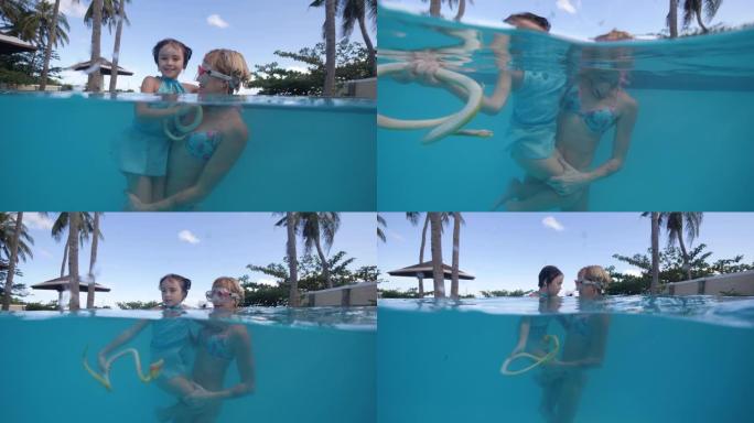 儿童女孩和妈妈在游泳池里用玩具蛇洗澡在热带酒店用手掌。