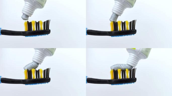 带有碳斑点的蓝色牙膏被轻轻地从管子中挤出到深蓝色的刷子上。刷毛和牙膏纹理的宏视频。口腔护理概念。