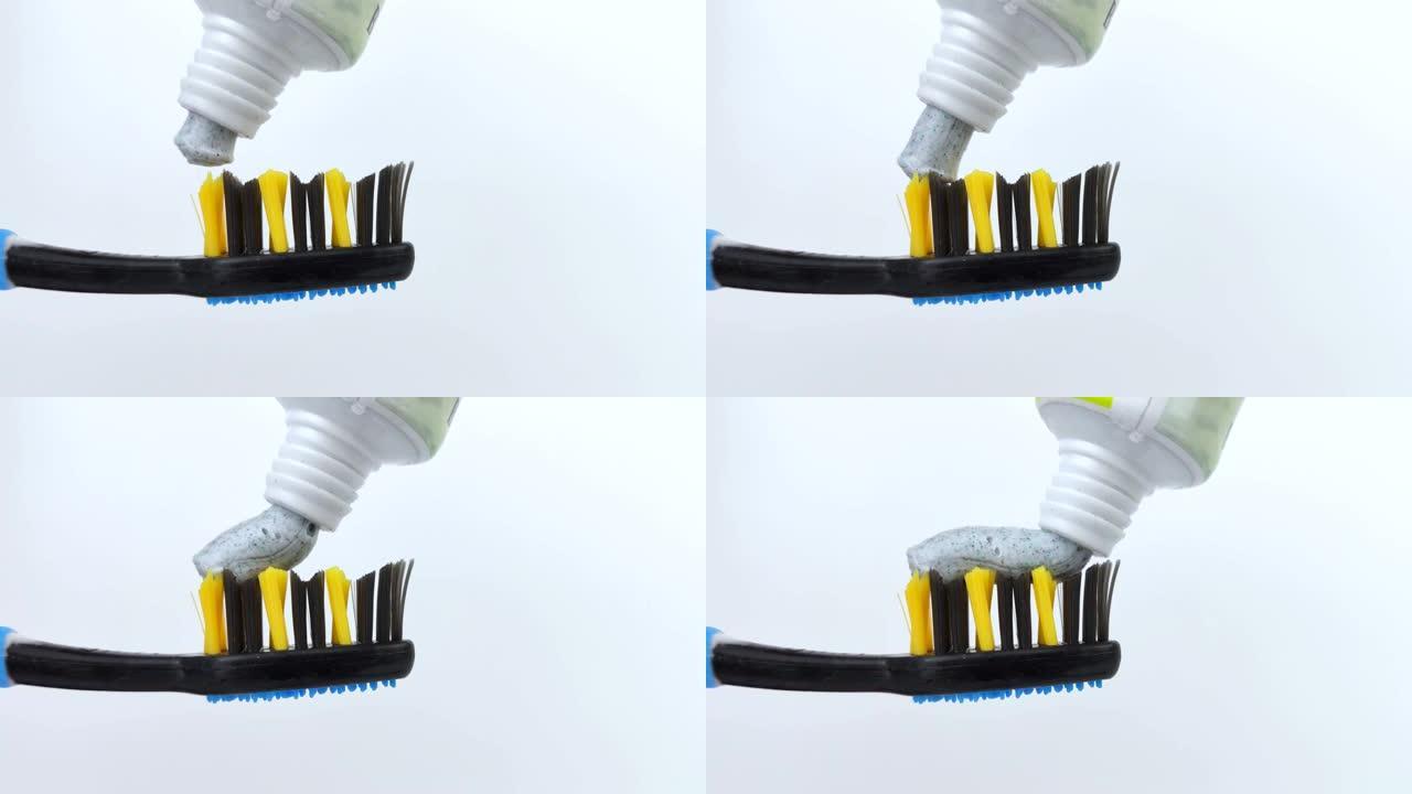 带有碳斑点的蓝色牙膏被轻轻地从管子中挤出到深蓝色的刷子上。刷毛和牙膏纹理的宏视频。口腔护理概念。