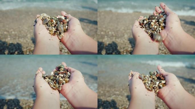 视点女性双手握着一把湿卵石。在海上休息，冥想概念