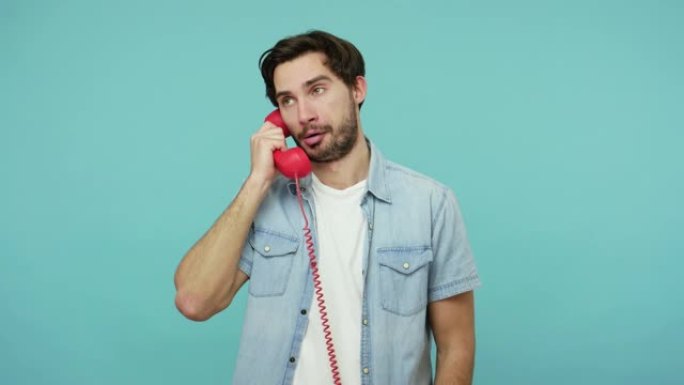 不满的家伙穿着牛仔裤衬衫接听电话，客户与联络中心沟通，红色电话听筒通话
