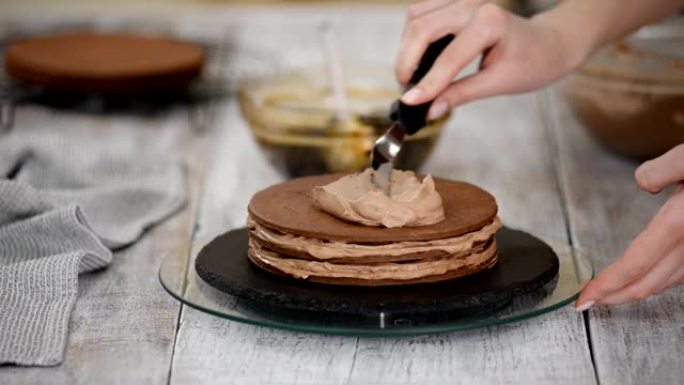 一步一步。糕点厨师用李子馅料制作巧克力层蛋糕。糖果店将奶油放在蛋糕上。