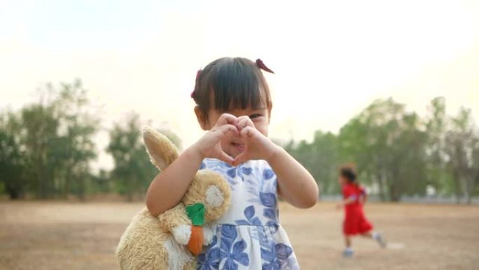 可爱的亚洲小女孩在公园里用爱拥抱泰迪熊。