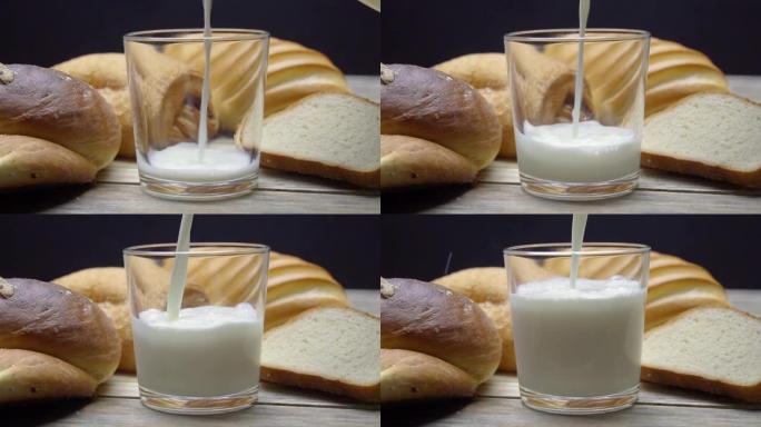 在乡村厨房里用面包和牛奶早餐。牛奶以慢动作倒入玻璃杯中。