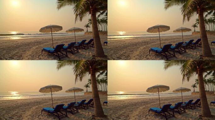 太阳伞椅海滩与棕榈树和海洋海滩在日出时间