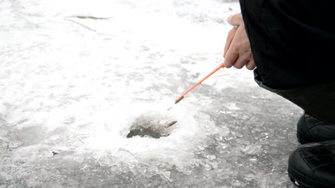 渔夫在冬季湖上的冰洞里钓鱼