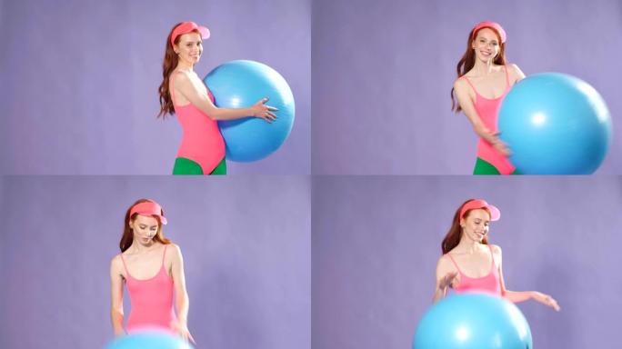 运动可爱的姜黄色女孩用蓝色健身球锻炼，热身锻炼
